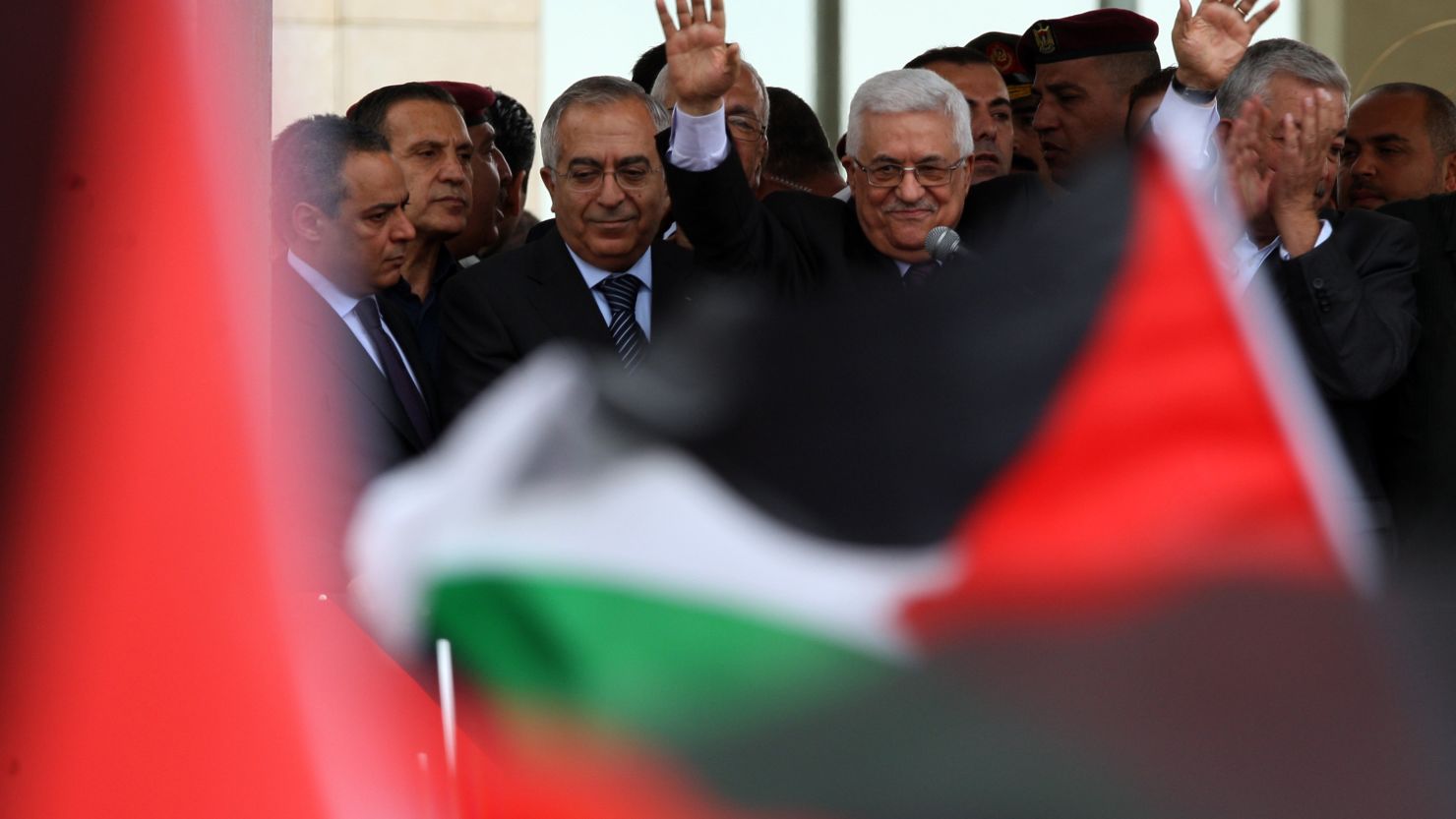 Palestinian President Mahmoud Abbas waves to Palestinians as they welcome him at his Ramallah headquarters Sunday.
