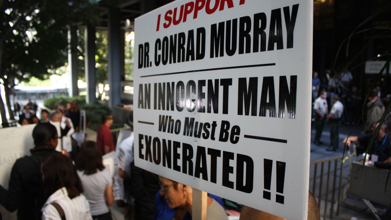 Supporters of Conrad Murray wave signs outside the courthouse.