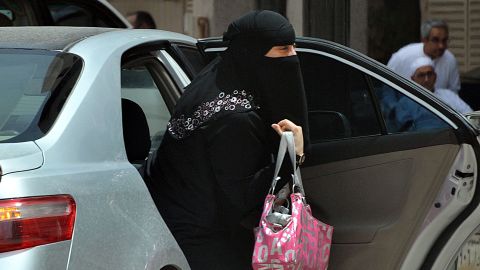 A Saudi woman gets out of the backseat of a car. Religious interpretations do not allow women to drive in Saudi Arabia.