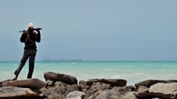 A pirate stands on a rocky outcrop on the coast of Hobyo, central Somalia, 2012