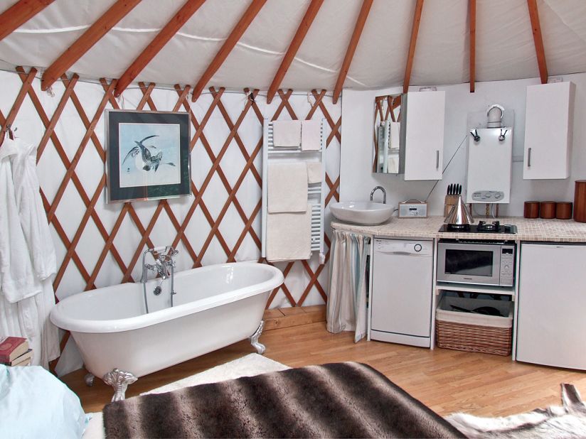 Within the yurt there's a kitchen with a dishwasher, a clawfoot tub, a dining area and a bed.