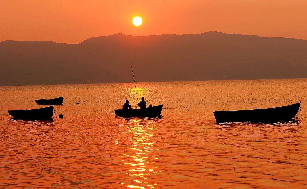 Two people fish on a boat on Macedonia's Lake Ohrid, one of the deepest and oldest freshwater lakes in Europe.