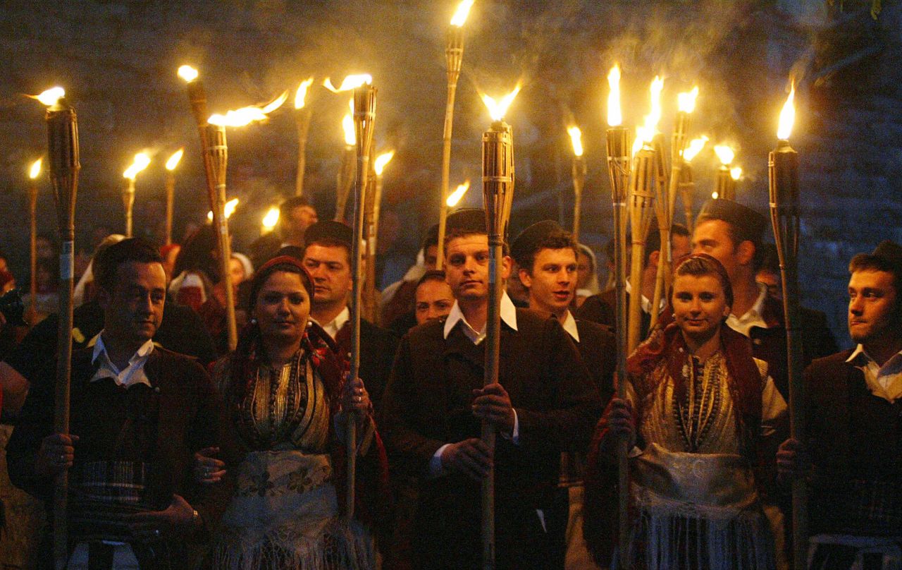 Orthodox christian men and women hold torches as they participate in a traditional Macedonian wedding procession.