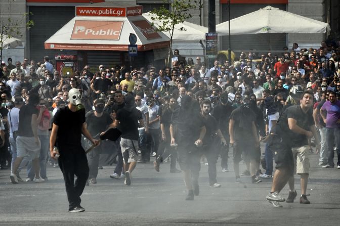 Demonstrators clash with police in the face of tear gas. The protests are part of a 24-hour general strike in the public sector that shut down Athens International Airport, government ministries and schools. Hospitals operated on skeleton staffs, and some commuter rail services were closed.