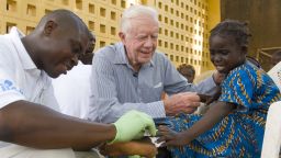 Former President Jimmy Carter consoles a child who has Guinea worm disease. 