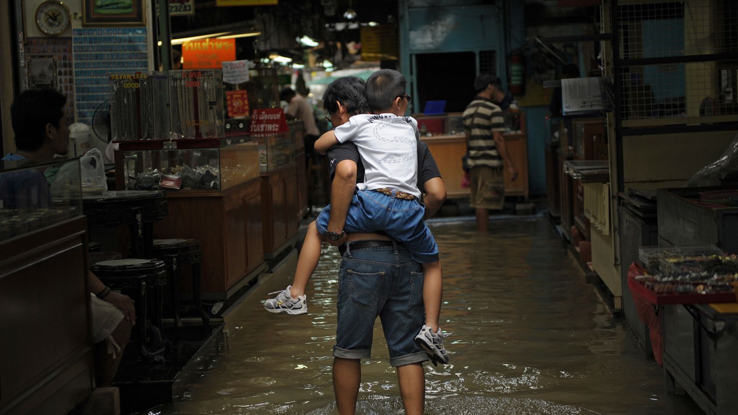 A man carries a boy on his back at a flooded market in a low-lying area of downtown Bangkok on 4 October.