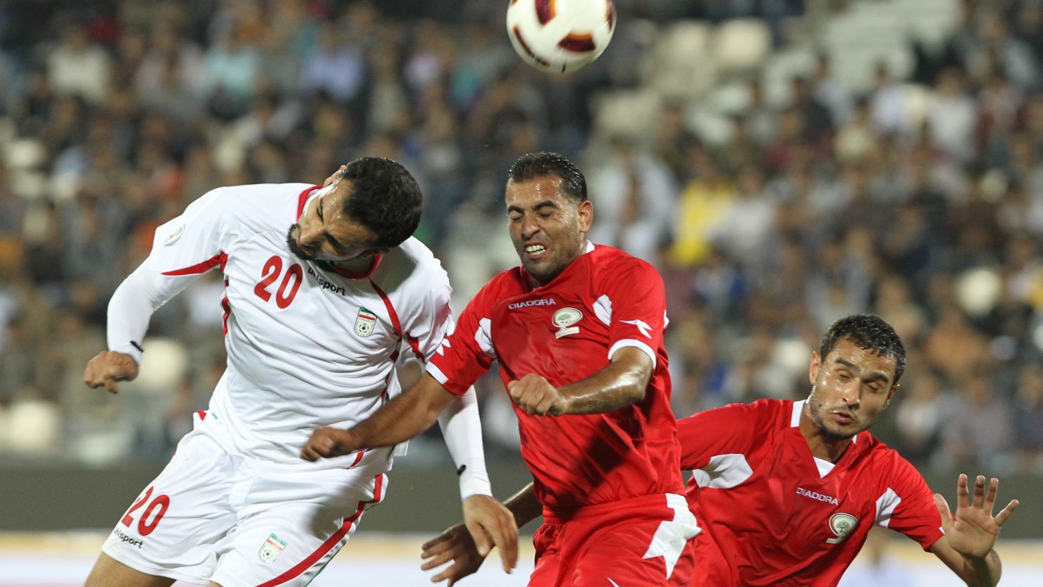 Iran's Mohammad Ghazi, left, leaps with Palestine midfielder Mali Kaware at Azadi Stadium on Wednesday.