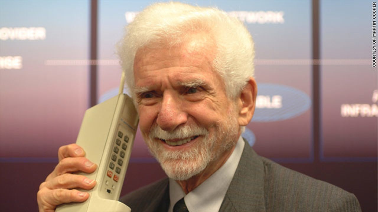 Martin Cooper hoists an early phone, the Motorola DynaTAC 8000X. Cooper made what is widely considered to be the first cellphone call from a New York City sidewalk in 1973.