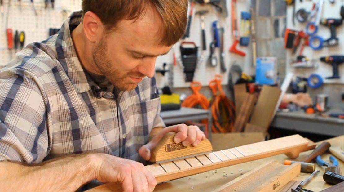 Dr. Withrow uses tight precision while working on a guitar neck.