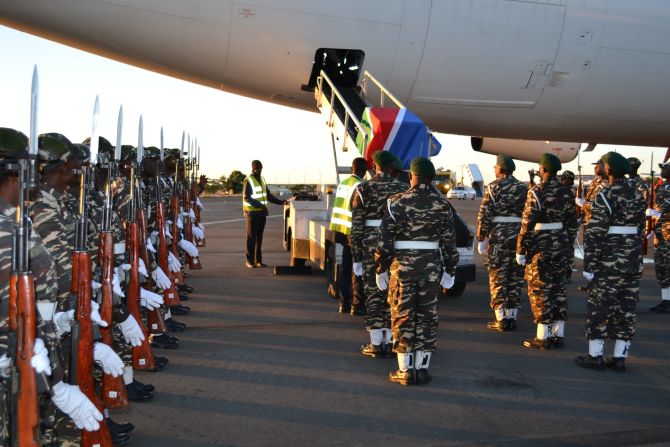 One of two caskets, each containing 10 skulls, is removed from the plane with military honors.