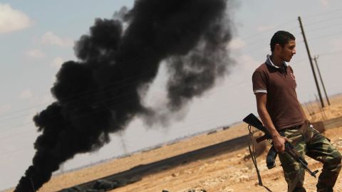 A National Transitional Council fighter walks past a plume of black smoke at the frontline in Bani Walid on October 4. 
