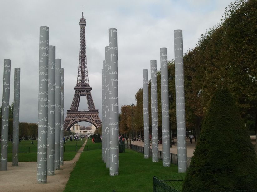 The Eiffel Tower peeks through the Wall of Peace monument on the Champ de Mars.
