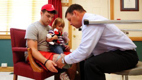 Roger Howard helps Matthew Hayes, with his daughter, get fitted for a new prosthetic leg.