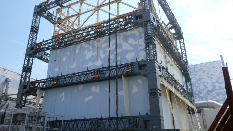 A Fukushima Daiichi reactor building is covered by a steel frame to prevent dispersal of radioactive materials.