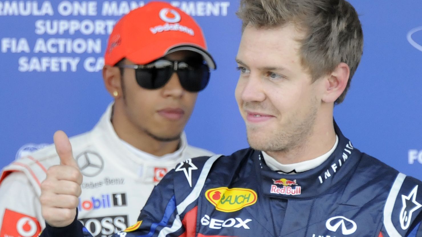 Red Bull driver Sebastian Vettel gestures to celebrate his pole position at Suzuka, as Lewis Hamilton looks on.