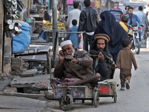 A disabled  beggar looks on as another beggar talks on a mobile phone in a market in Rawalpindi, Pakistan, on November 19, 2008. A 2006 University of Michigan study found that every 10% increase in cell phone penetration grows the local economy by 0.6%.