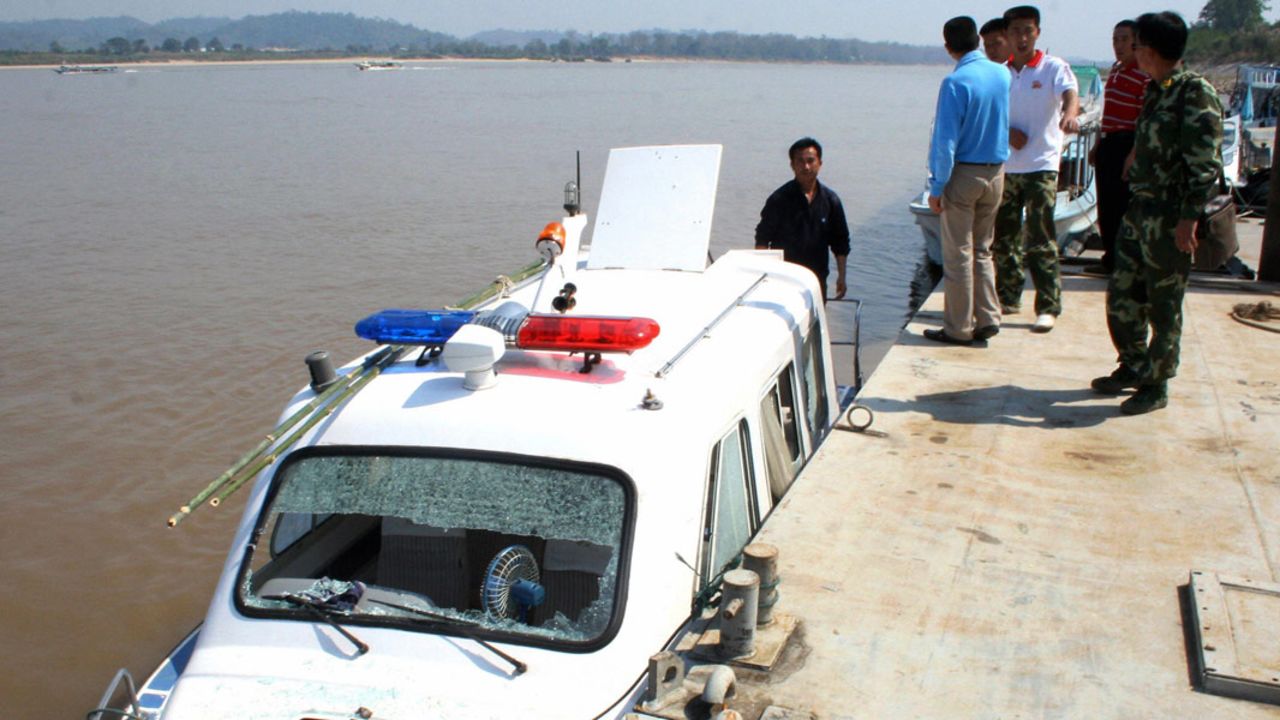 Chinese policemen look at their damaged patrol boat after a gunfight with drug traffickers in Chiang Rai on February 25, 2008.   