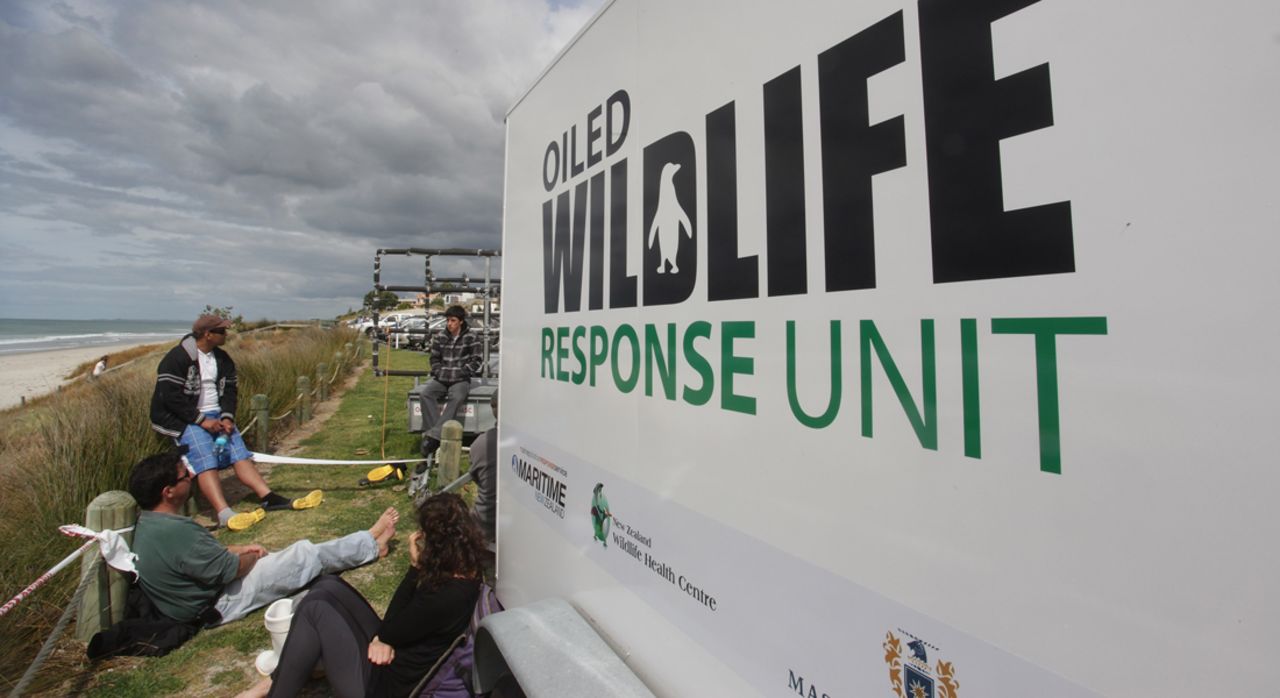 Volunteers wait for a debriefing next to an Oiled Wildlife Response Unit at Omanu Beach on October 8 in Tauranga.