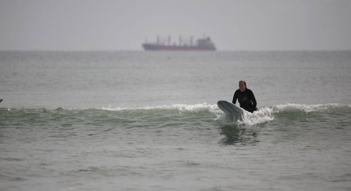 A surfer catches a wave with the main cargo route in the background near the port of Tauranga on October 8. 