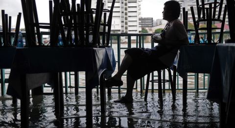 A Thai employee of a riverside restaurant sits idle as water from a river floods low-lying areas of Bangkok on October 4, 2011. 
