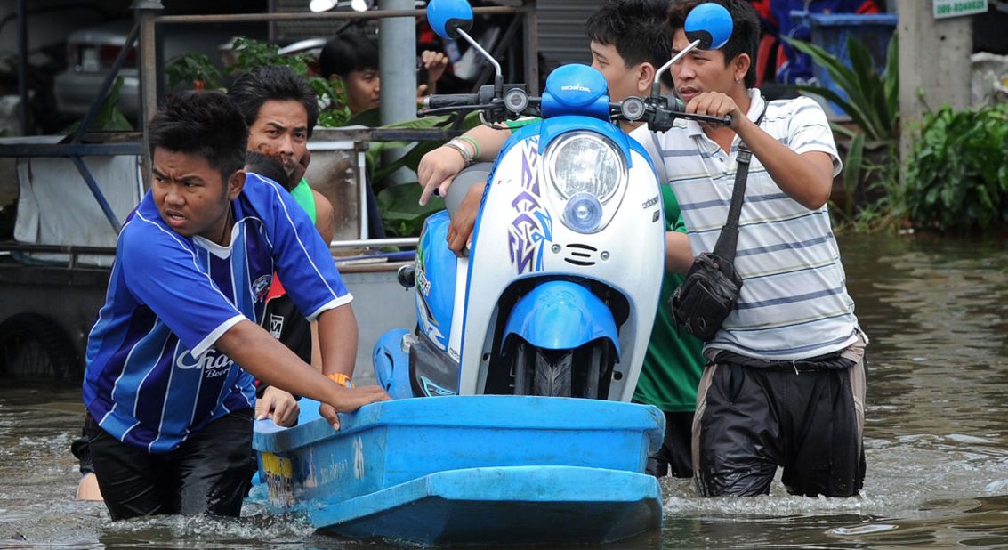 Thai residents transport a scooter over floodwaters along a street in the city of Ayutthaya on October 6, 2011. 