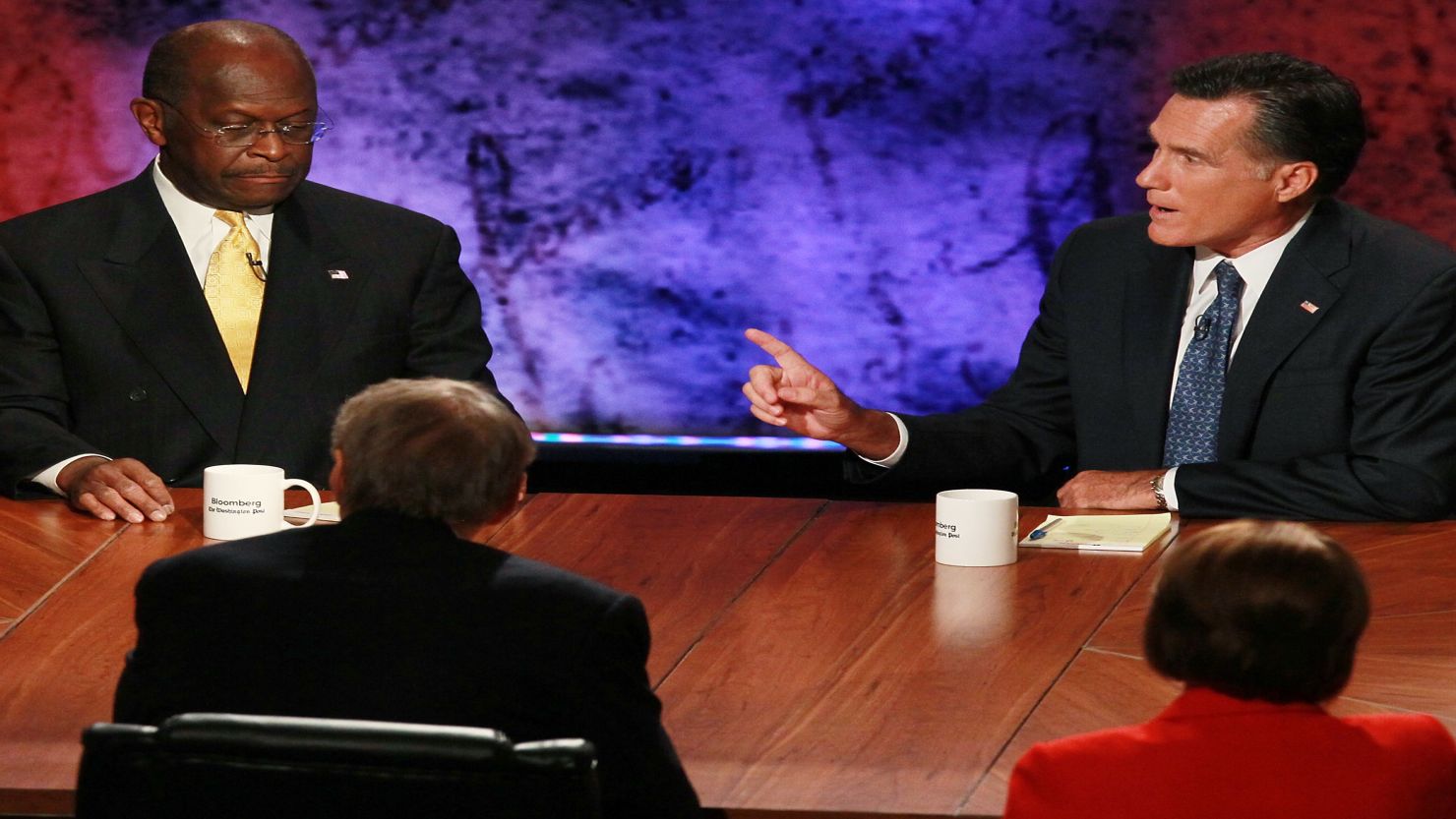 Mitt Romney, right, makes a point as Rick Perry, left, and Herman Cain listen at the GOP presidential debate October 11.