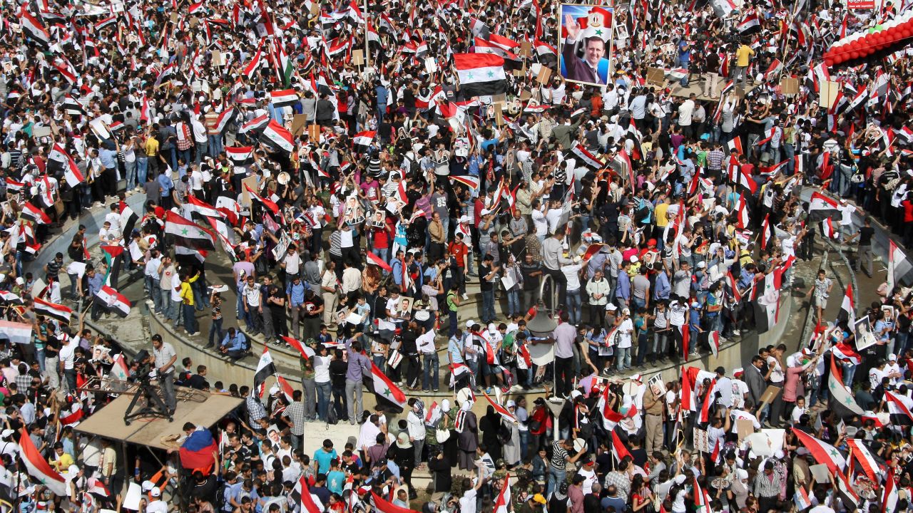 Supporters of Syrian President Bashar al-Assad wave Syrian flags during a pro-regime rally in Damascus on October 12.