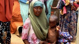 An internally displaced person holds her malnourished child in front of her makeshift shelter on August 25, 2011, at the Taraboonka IDP camp in the Hodon district of Mogadishu.