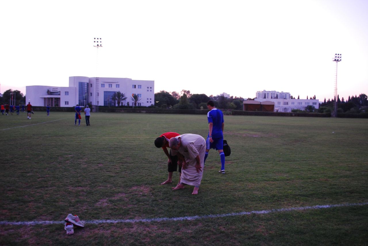 Members of the Libyan team's backroom staff pray after training.