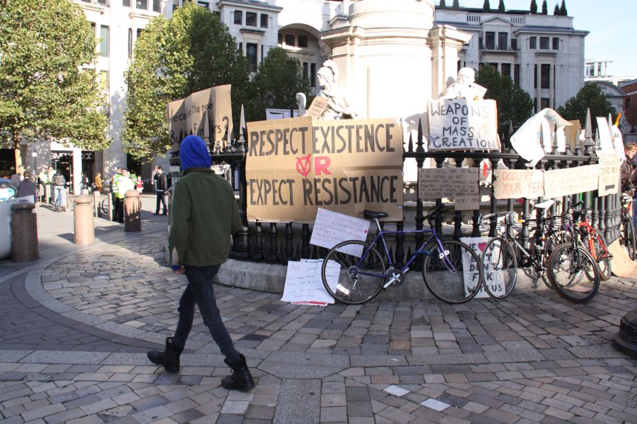A demonstrator walks past signs at the protest camp outside St Paul's Cathedral in London.