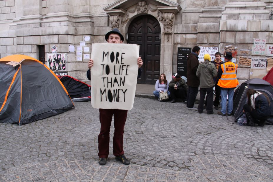 Occupy London protester James Banks holds up a poster reading "More to life than money."