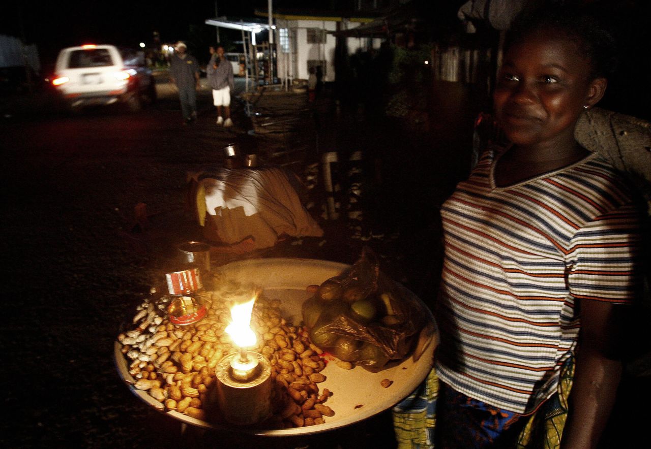 A street vendor lights her stand with a candle in July 2006 in Sierra Leone's capital, Freetown.