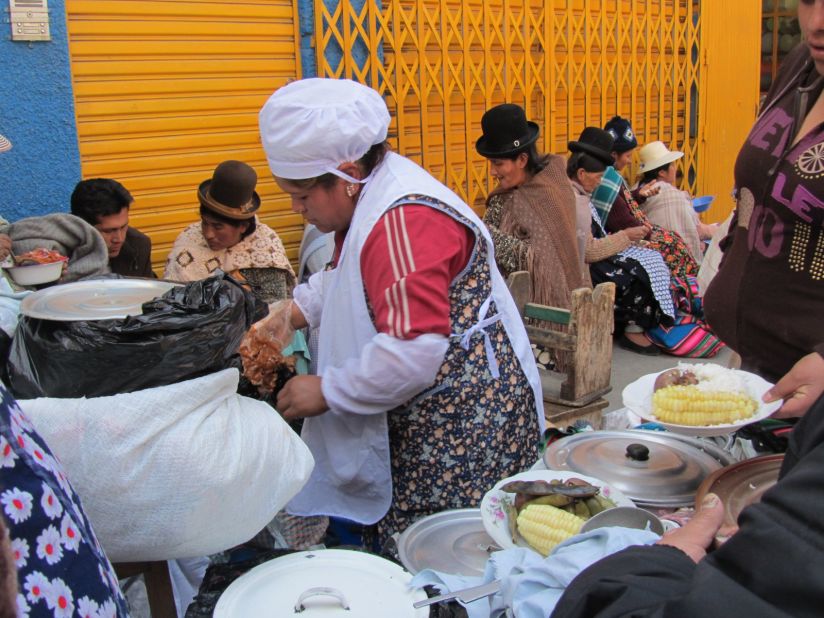 A woman serves plates of potatoes, corn, rice and meat. Markets throughout the city offer the chance to eat like a local.