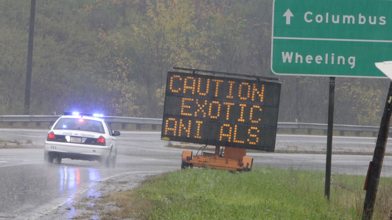 A police officer drives past a sign warning of wild animals on the loose on October 19  in Zanesville, Ohio. 