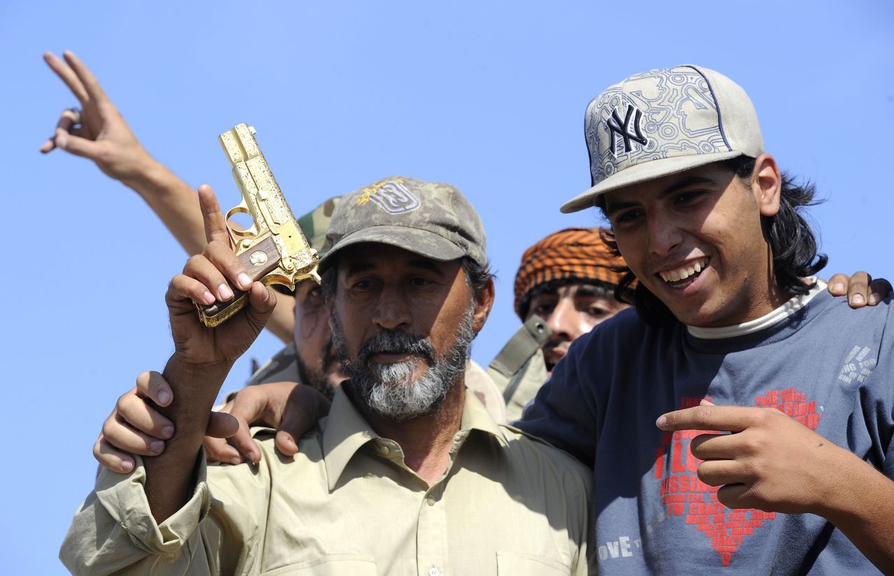 NTC fighters hold what they say is the ousted Libyan leader's gold-plated gun Thursday.