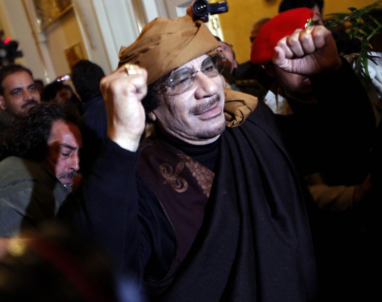 Gadhafi smiles and raises his arms as he enters the Rixos Hotel in Tripoli on March 8, 2011. A few months later, on October 20, Gadhafi will die of a gunshot wound to the head in his hometown of Sirte, Libya.