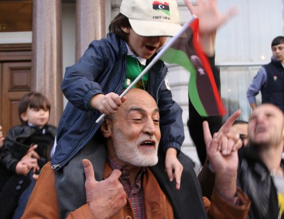 A man dances with a child on his shoulders outside the Libyan Embassy in London.
