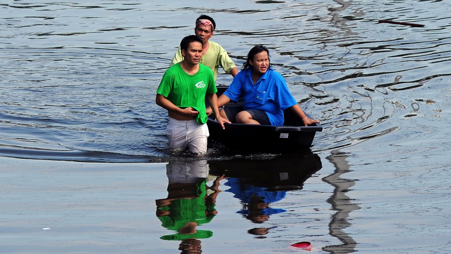 Bangkok residents cross flood waters as Thailand prepares for more rain.