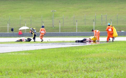 Marshalls rush to assist Simoncelli after he crashed on his Honda (no58) at Sepang.
