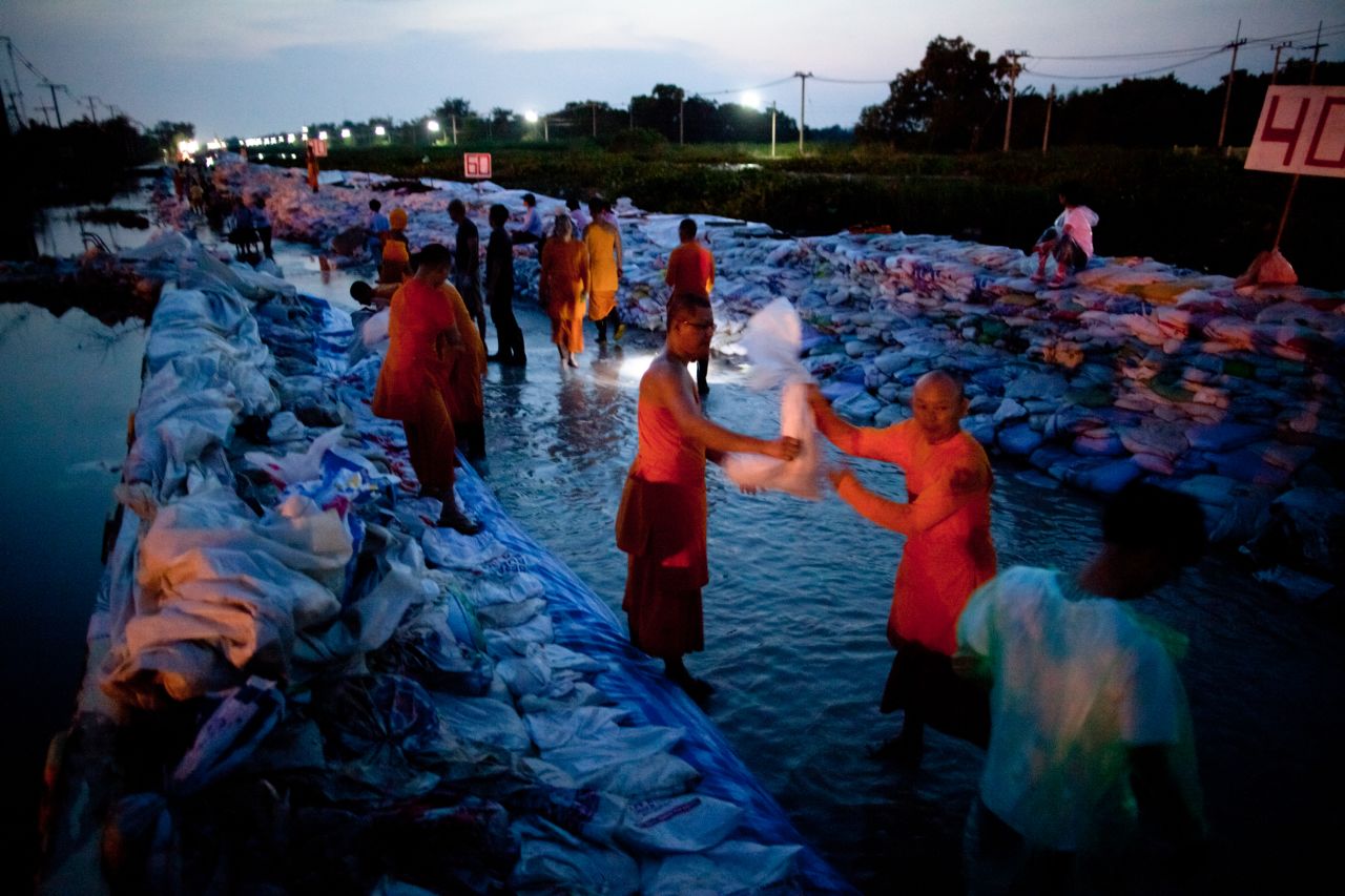 Dhammakaya monks and volunteers work to fortify the flood gate at Klong Rapi Pat Sunday on the outskirts of Bangkok, Thailand.