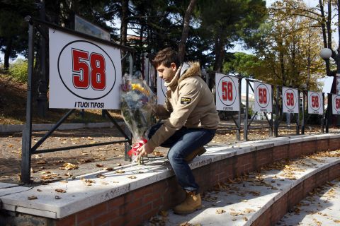 An Italian MotoGP fan lays flowers under Simoncelli's race number in the town of Cattolica.