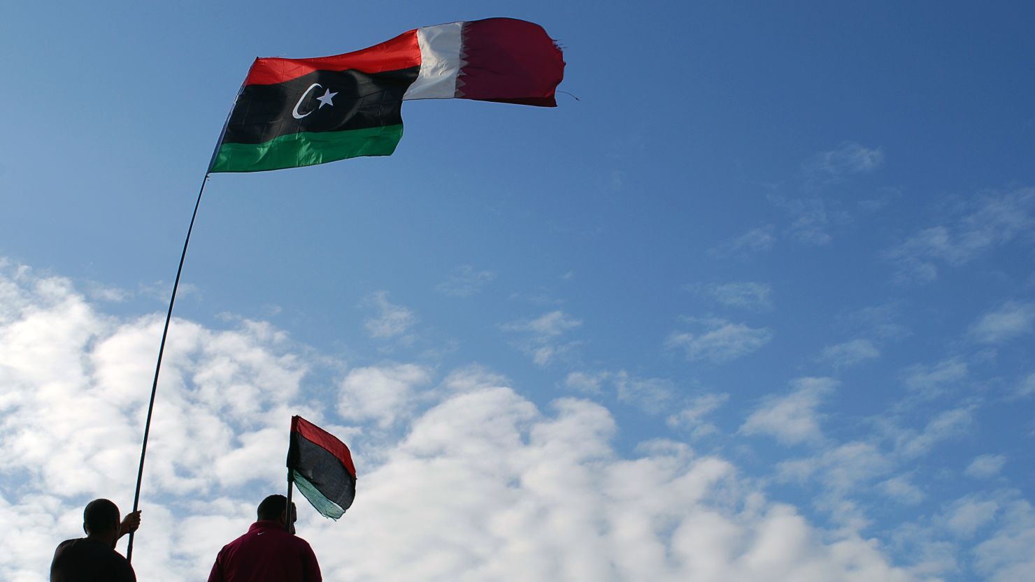 Libyans wave their new national flag and Qatar's flag during a ceremony announcing the liberation in Benghazi on Sunday.