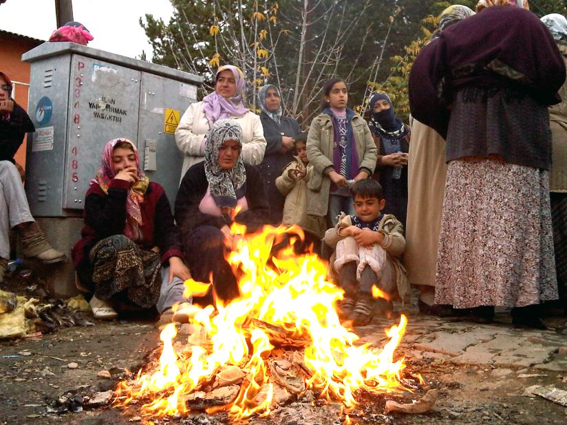 Residents of Ercis gather around a fire to keep warm as they wait in the streets on Tuesday for news of survivors.