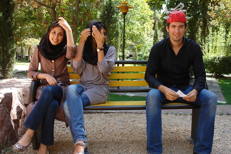 Theme park expert, Stefan Zwanzger, wearing his trademark roller coaster hat, sits next to some young Iranian women.