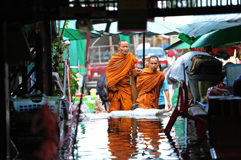 Buddhist monks walk toward a pier along the Chao Phraya River, which winds through the capital.