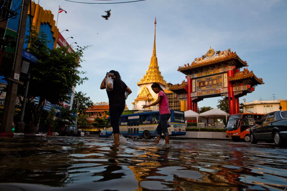 People walk through a flooded street in Bangkok's Chinatown on Wednesday. Thailand derives a significant portion of its revenue from tourism, which has been diminished by the flooding.