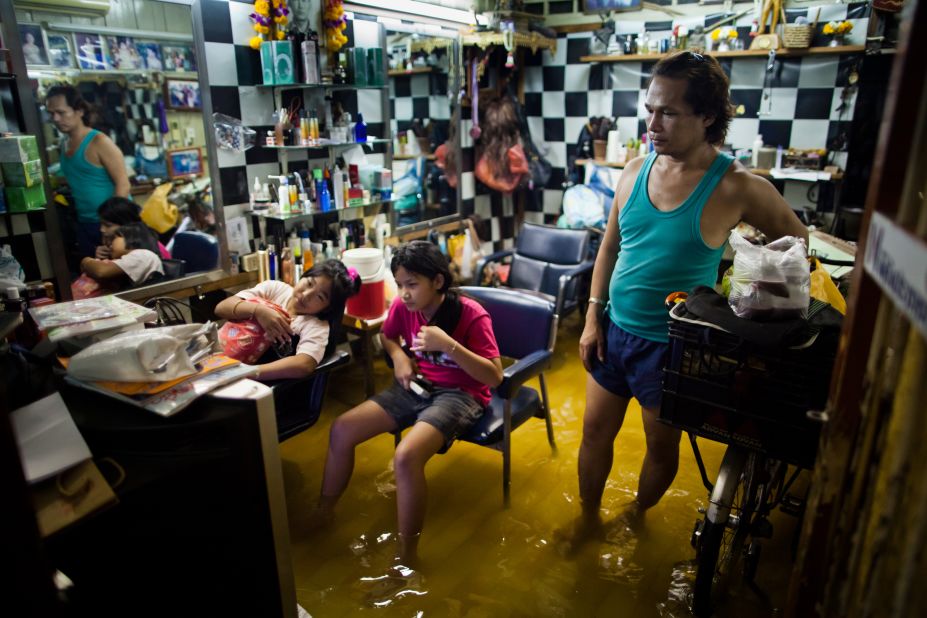 Bangkok residents watch television in a flooded beauty salon on Wednesday.