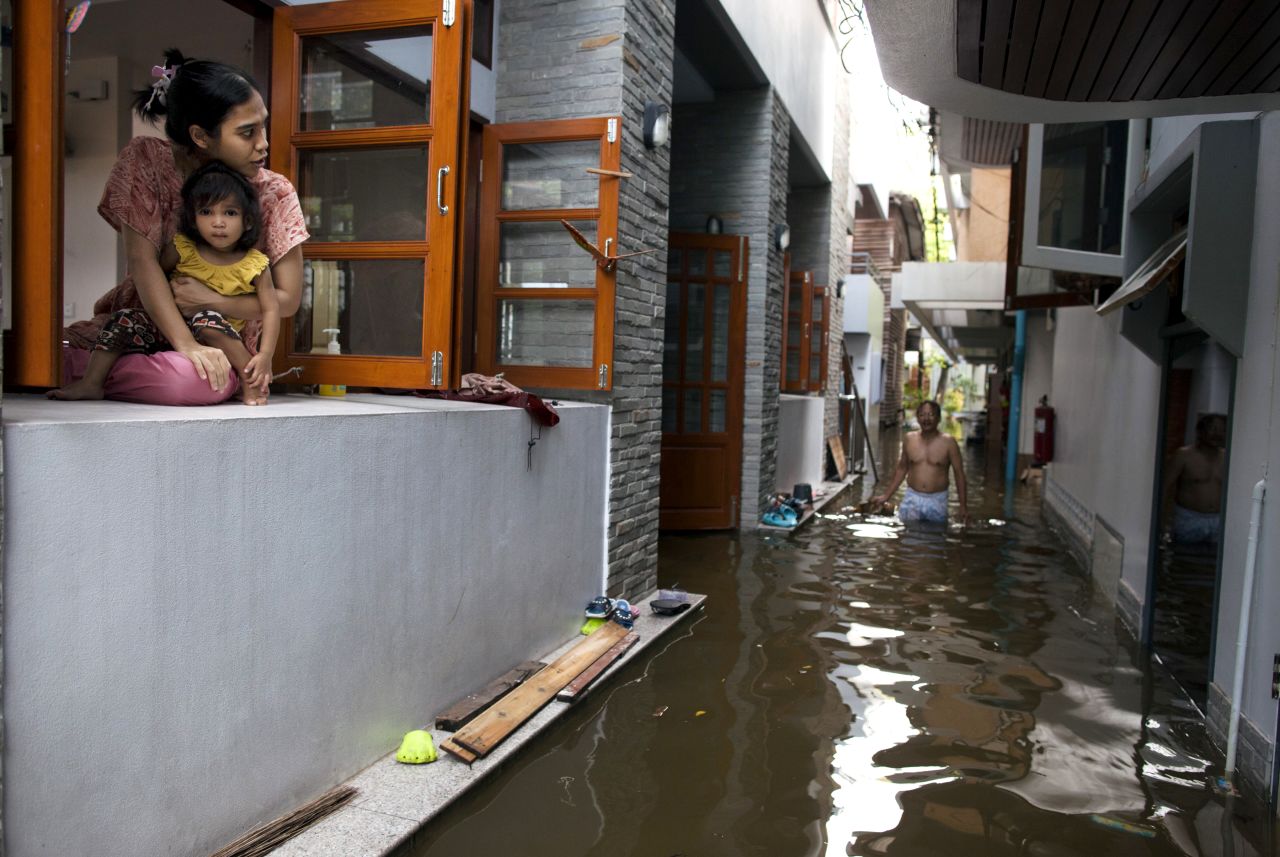 A woman sits with her daughter in the window of their flooded condo. Residents have been urged to flee the rising waters.