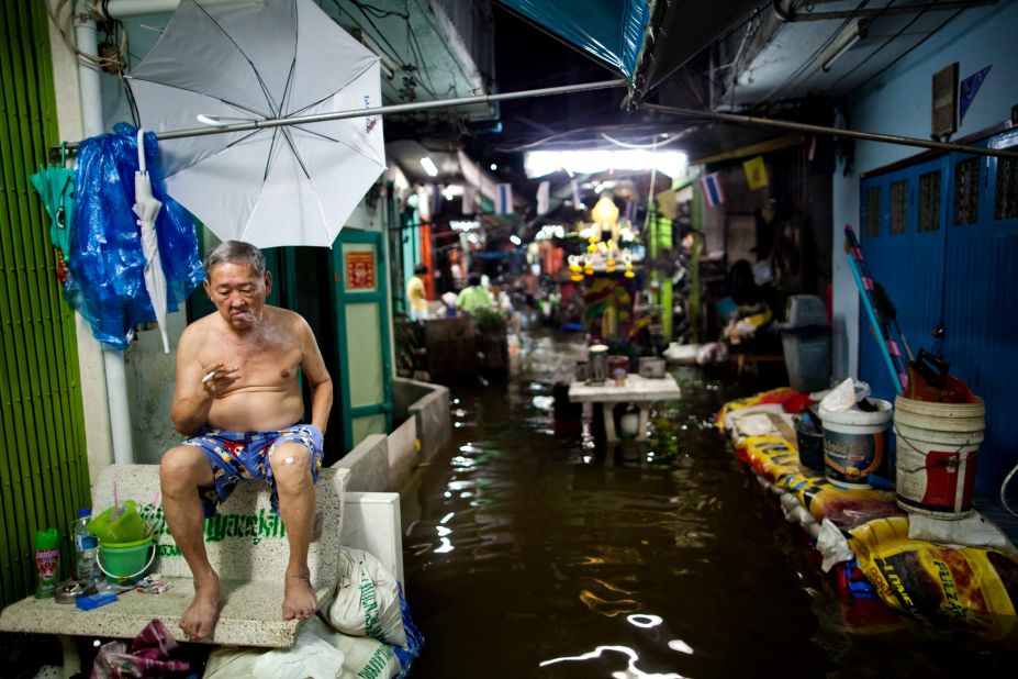 A man smokes a cigarette outside his home as floodwaters rise in Bangkok on Wednesday, October 26. The government has called the flooding the worst to afflict the nation in half a century.