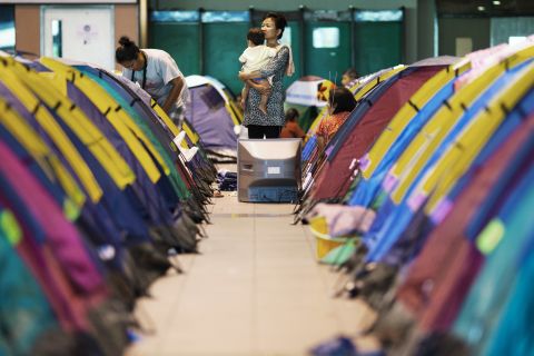 Evacuated residents stand among tents in a shelter set up for flood victims at Don Muang airport. Floodwaters forced the airport to close, and it now serves as a base of flood relief operations.
